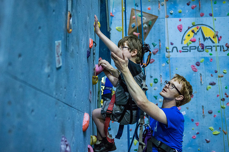 Instructor teaching a young boy to wall climb