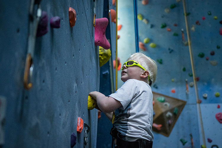 Young boy with seeing glasses wall climbing