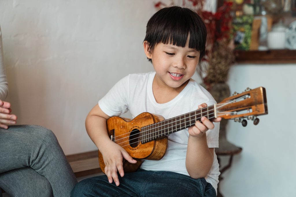Boy in white t-shirt playing ukulele