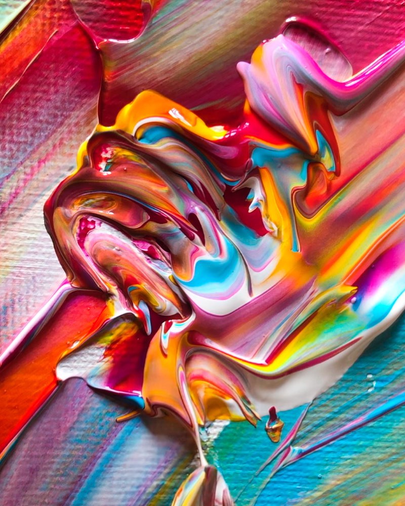 A small cross-section of an abstract expressionist painting. Bands of bright neon paint spread across the canvas in pink, yellow, blue and white. A swirl of acrylic paint sits in the centre in a squiggled application.
